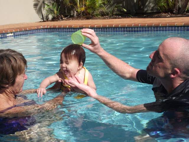 A family swim lesson in a sunny backyard pool