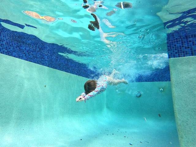 A young child diving confidently underwater in a backyard pool